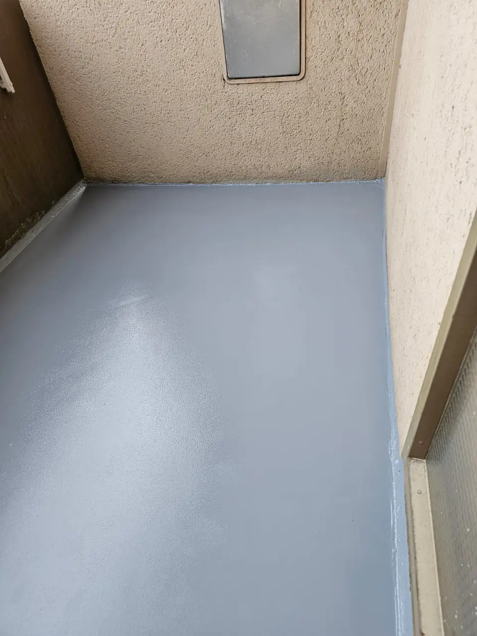 Sanierter Balkon mit neuer grauer Bodenbeschichtung