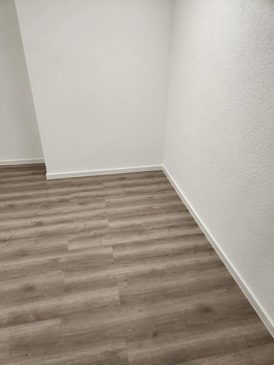 Schmaler Raum nach dem Ausbau mit Bodenbelag in Holzoptik