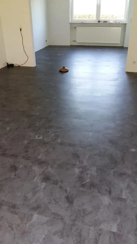 Verlegen dunkler großformatiger Bodenfliesen in einem Neubau